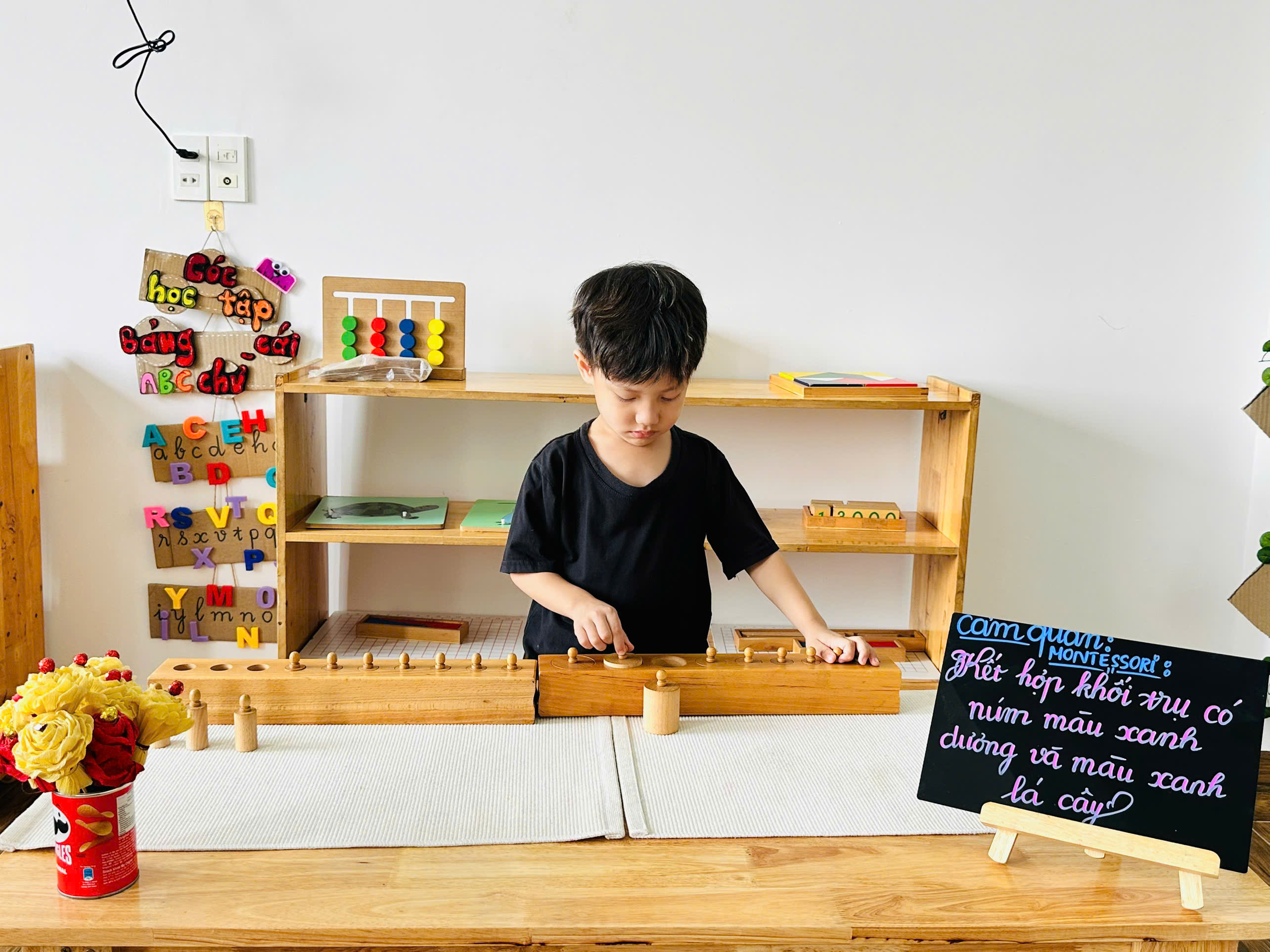 Trẻ tập trung so sánh và ướm từng khối trụ có núm vào đúng ổ