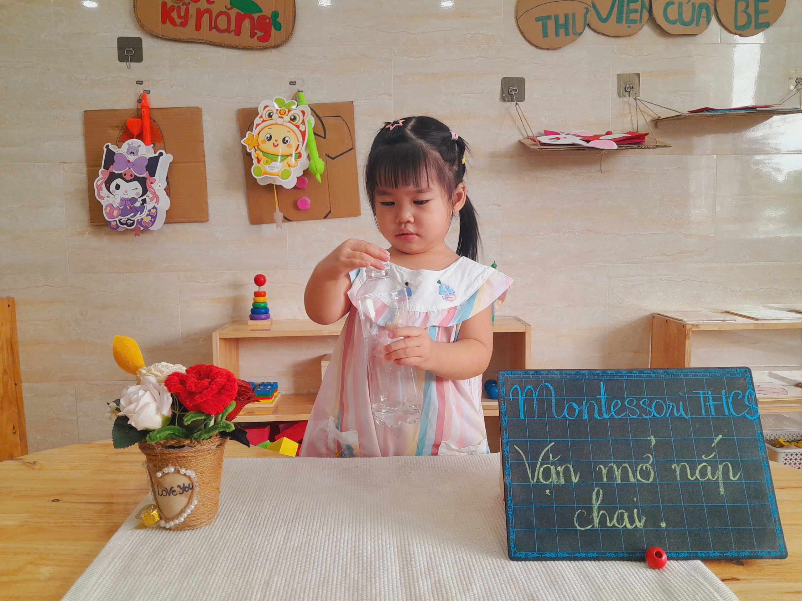 Giáo viên hướng dẫn bé vặn mở nắp chai theo phương pháp Montessori