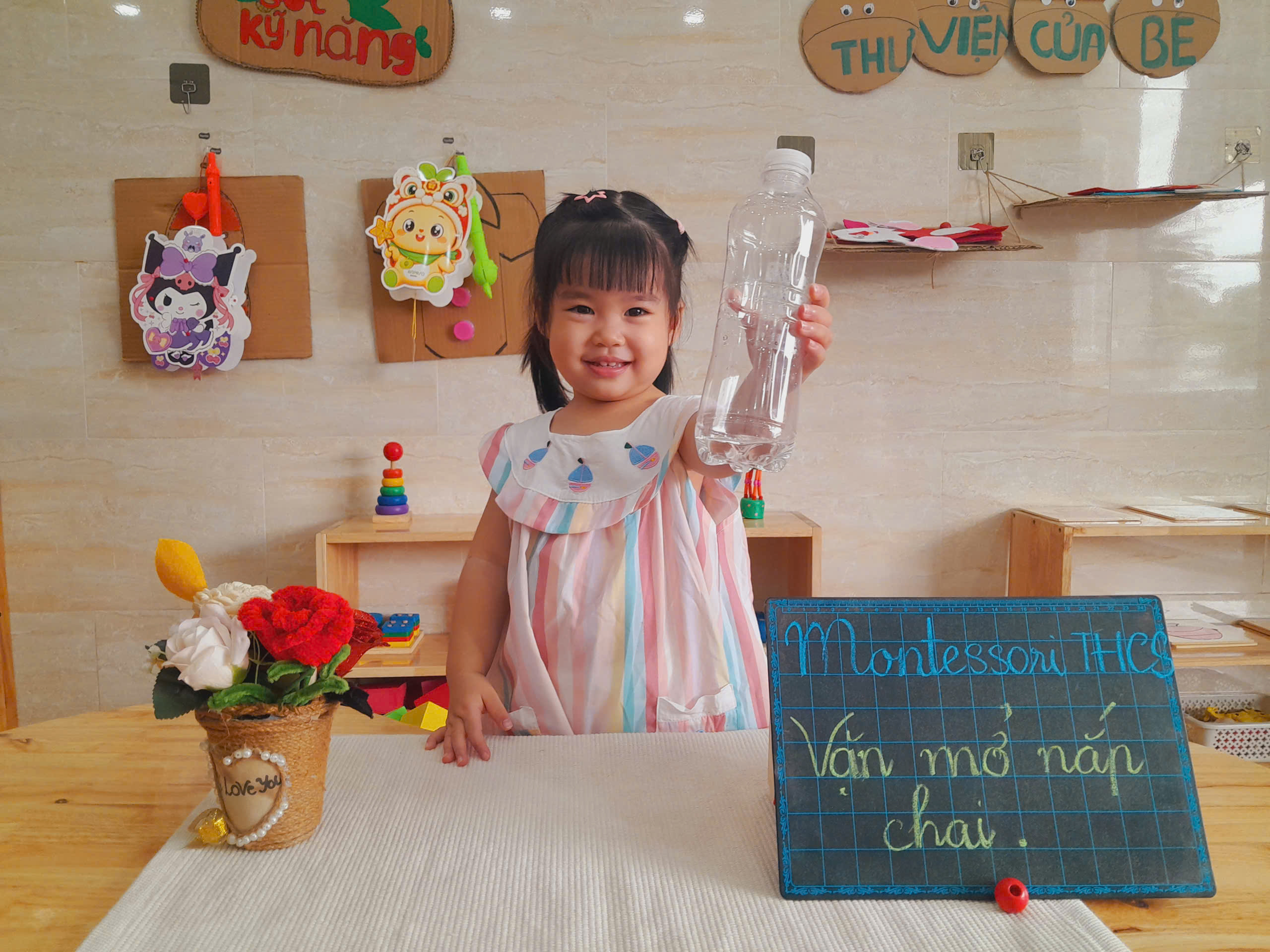 Bé kiên nhẫn thực hành vặn mở nắp chai tại lớp Montessori Kim Hà